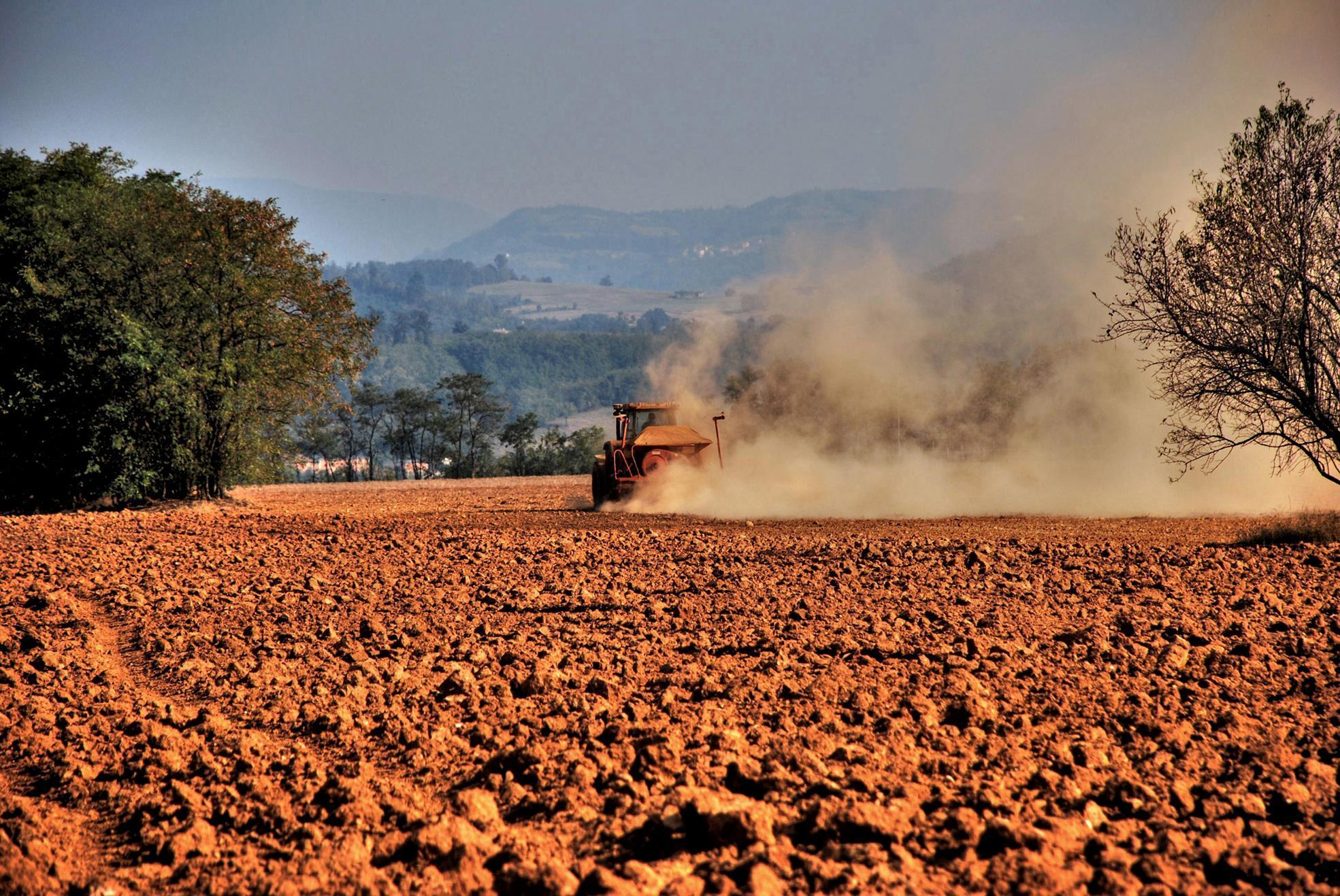 Un trattore dissoda un terreno inaridito dalla siccità