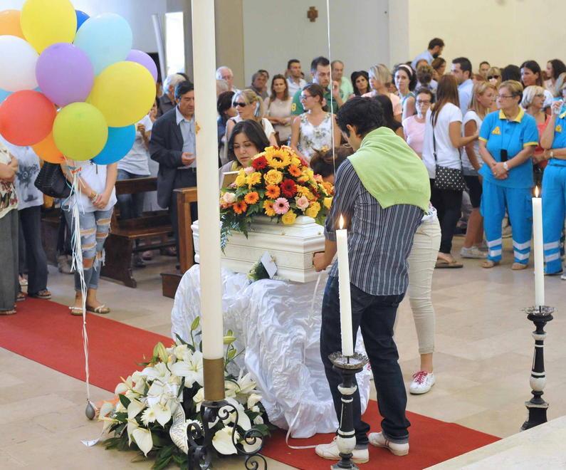 I genitori portano la piccola bara bianca in chiesa accanto ai palloncini colorati (Foto Gori)