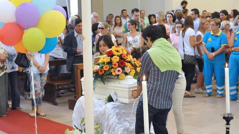 I genitori portano la piccola bara bianca in chiesa accanto ai palloncini colorati (Foto Gori)