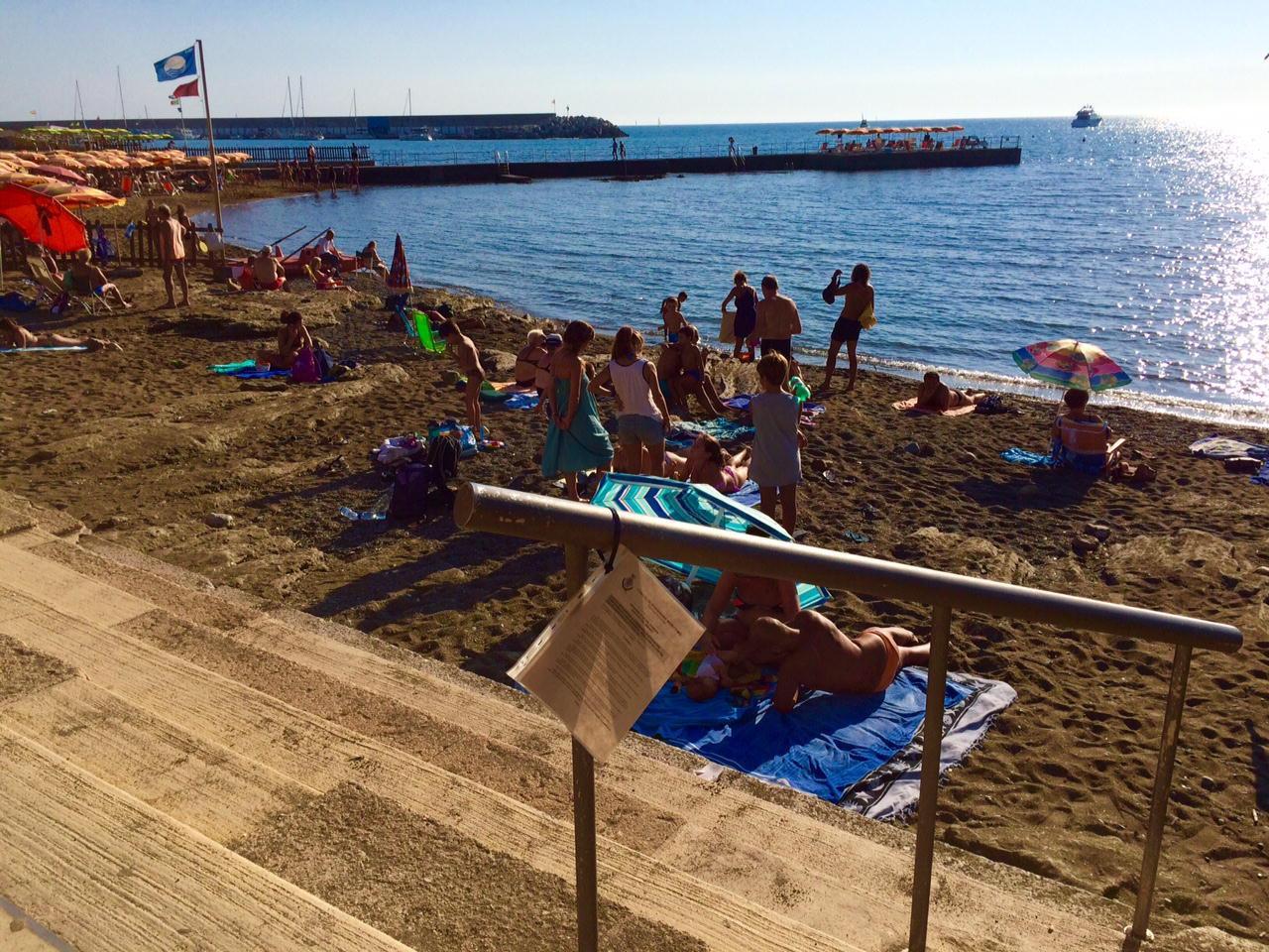 Turisti in spiaggia a Caletta con il foglio del divieto di balneazione