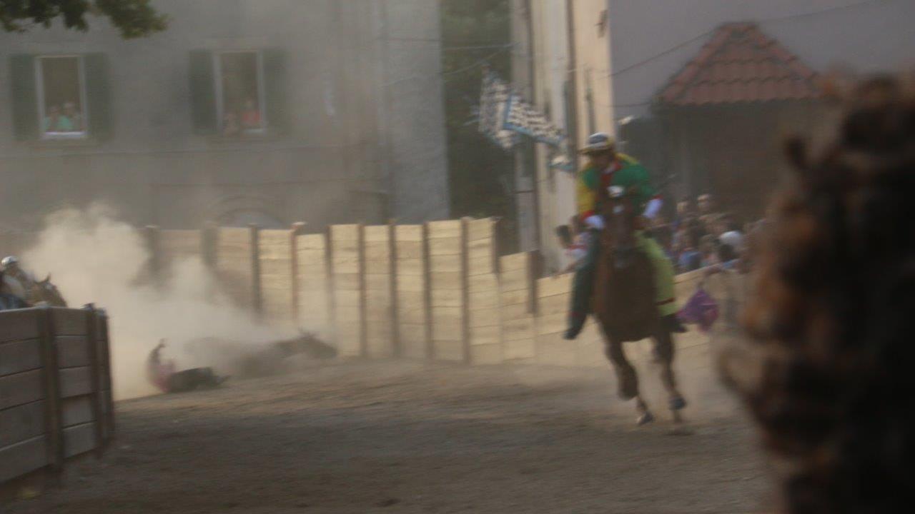 Sullo sfondo il fantino del Borgo, Antonio Siri, e il cavallo Quativoglio a terra. In primo piano Giuseppe Zedde del Poggio verso la vittoria (foto Russo)