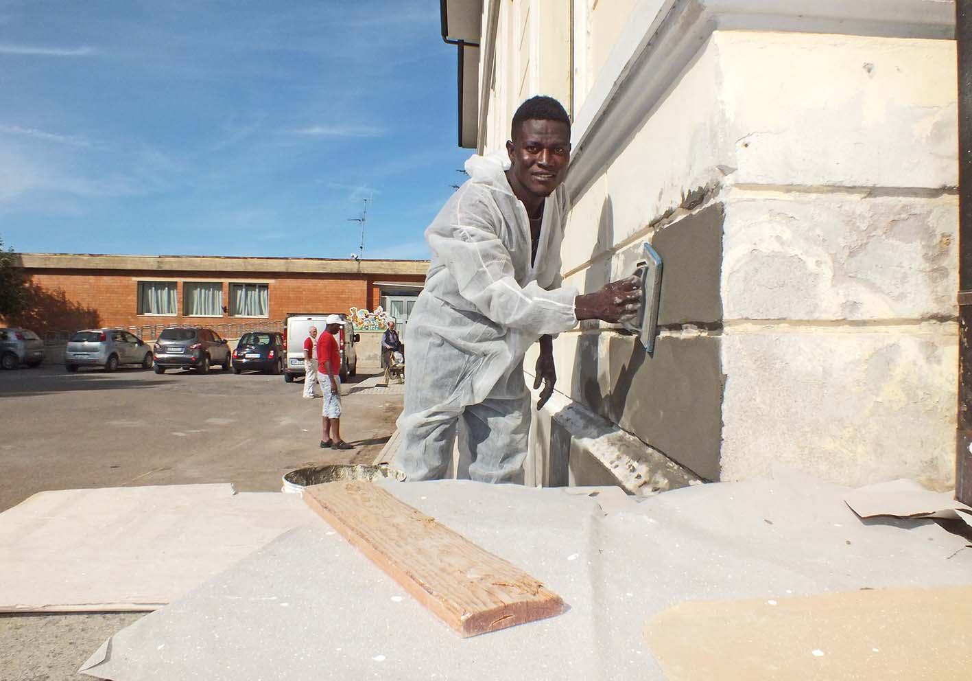 Un migrante mentre tinteggia la scuola
