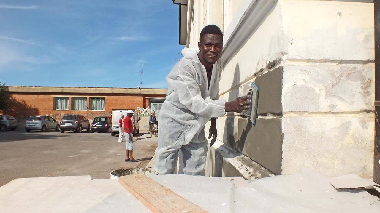 Un migrante mentre tinteggia la scuola