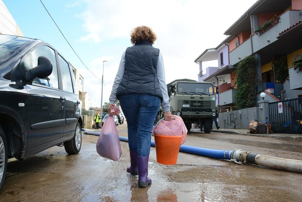 Un'immagine-simbolo: un'alluvionata di Olbia porta via alcune cose dalla sua abitazione (Foto Gavino Sanna)