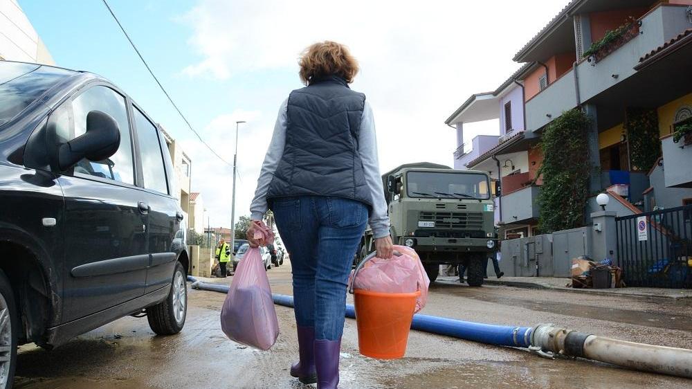 Un'immagine-simbolo: un'alluvionata di Olbia porta via alcune cose dalla sua abitazione (Foto Gavino Sanna)