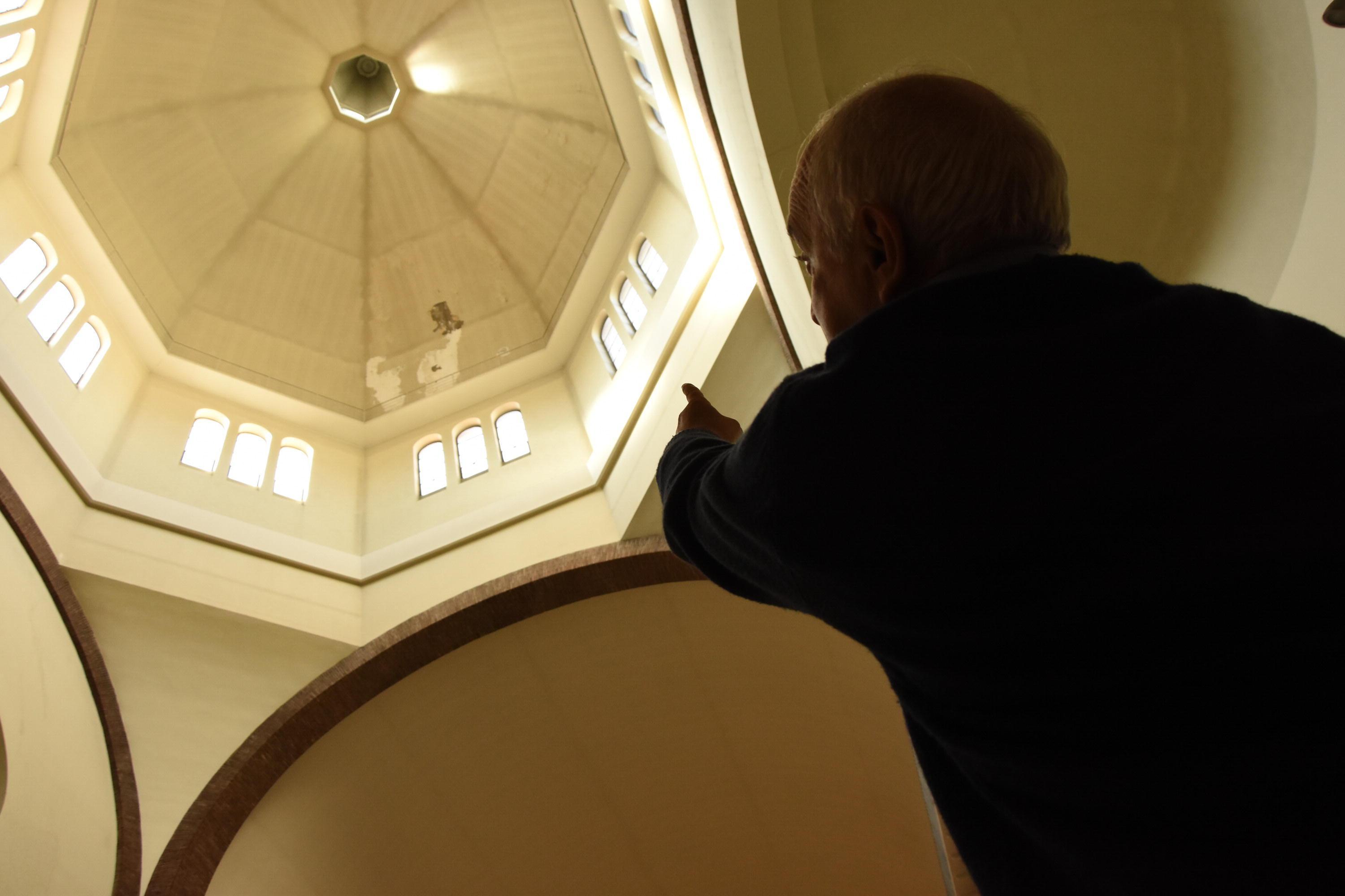 Padre Egidio indica l’intonaco staccato. Sopra, calcinacci sulle panche (Bf)