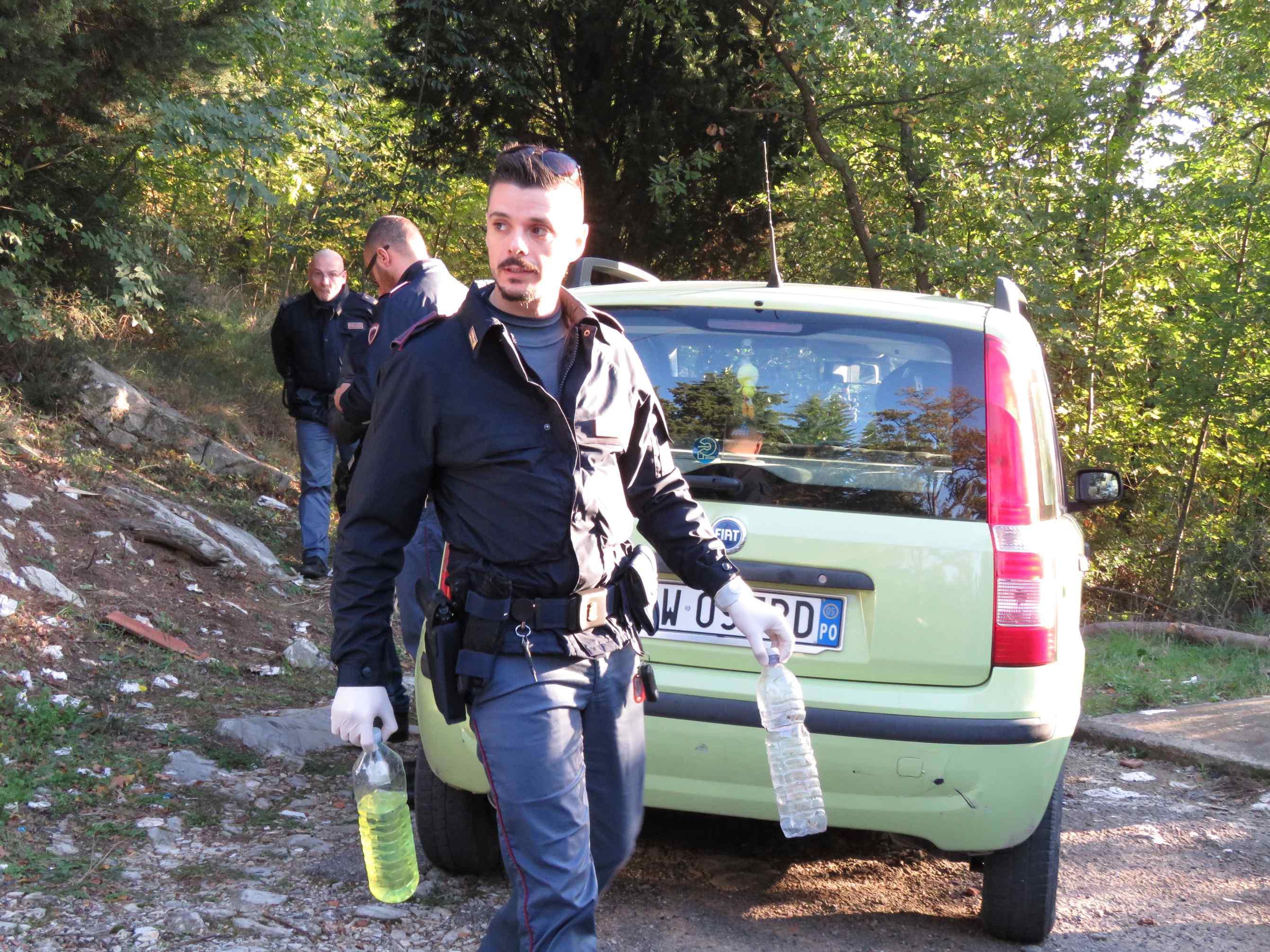 Un poliziotto delle volanti porta via le bottiglie piene di benzina (foto Batavia)