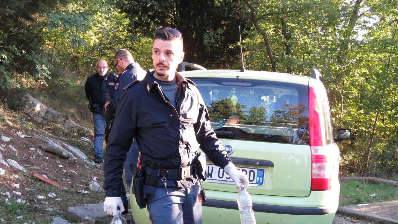 Un poliziotto delle volanti porta via le bottiglie piene di benzina (foto Batavia)