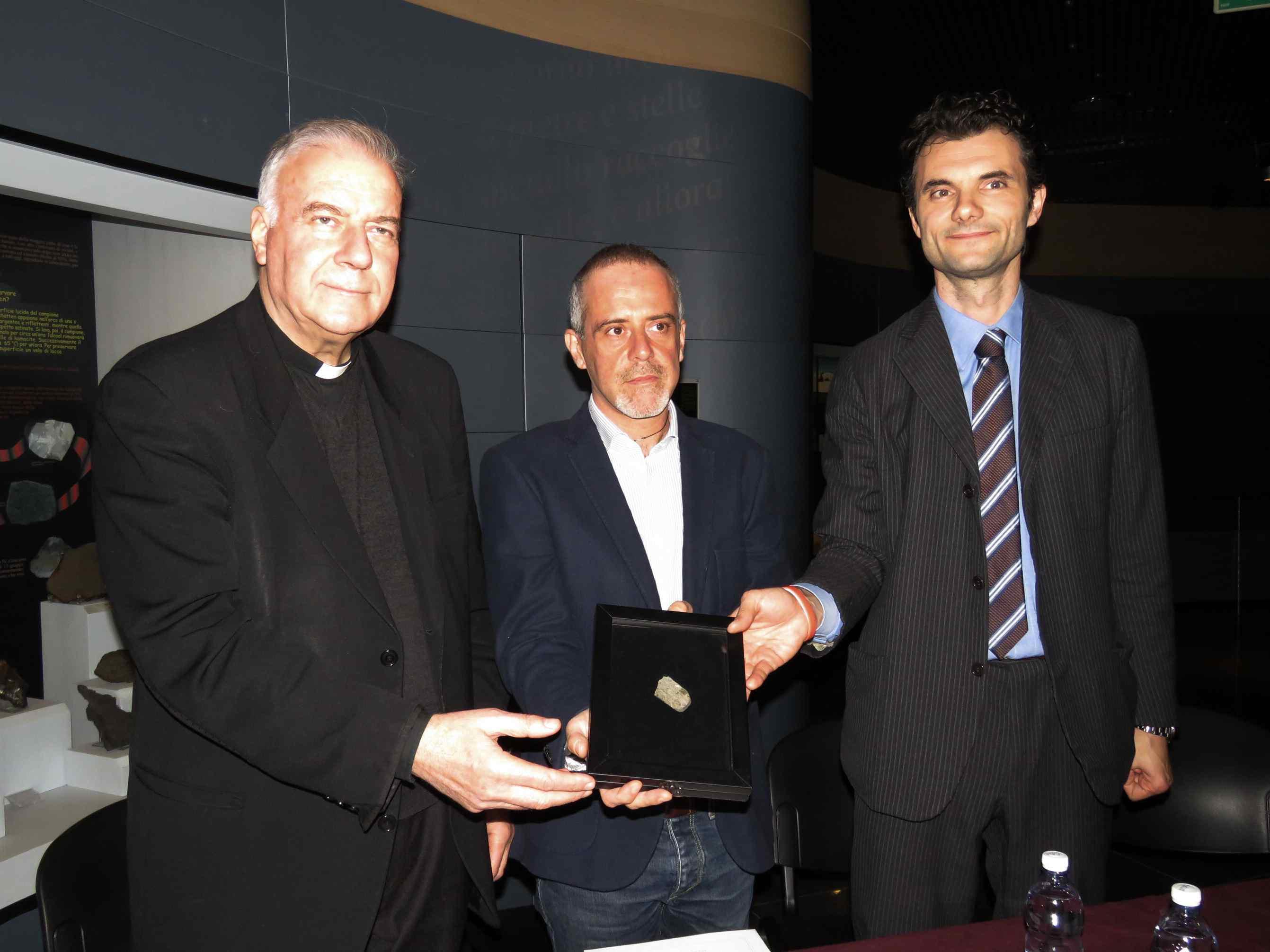 Il sindaco Biffoni, il vicario don Mannucci e il direttore Morelli mostrano il meteorite