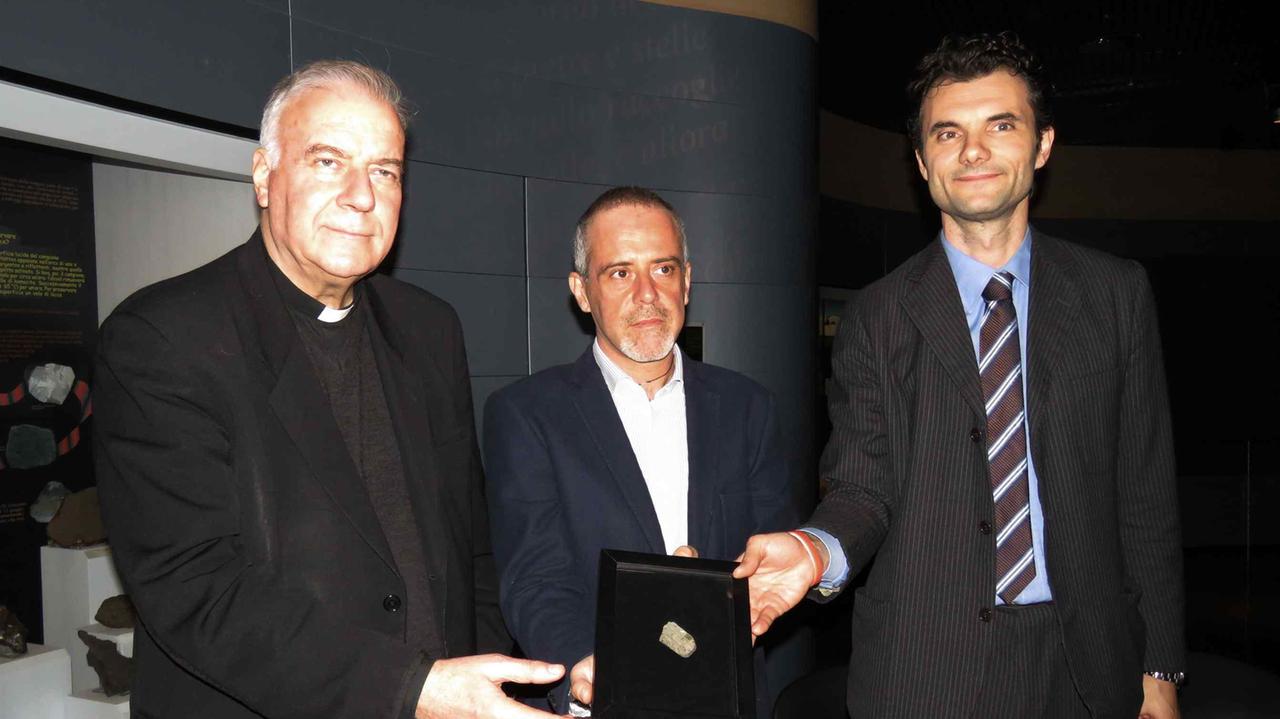 Il sindaco Biffoni, il vicario don Mannucci e il direttore Morelli mostrano il meteorite