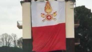 Il momento della scesa della bandiera tricolore da parte di tre vigili del fuoco