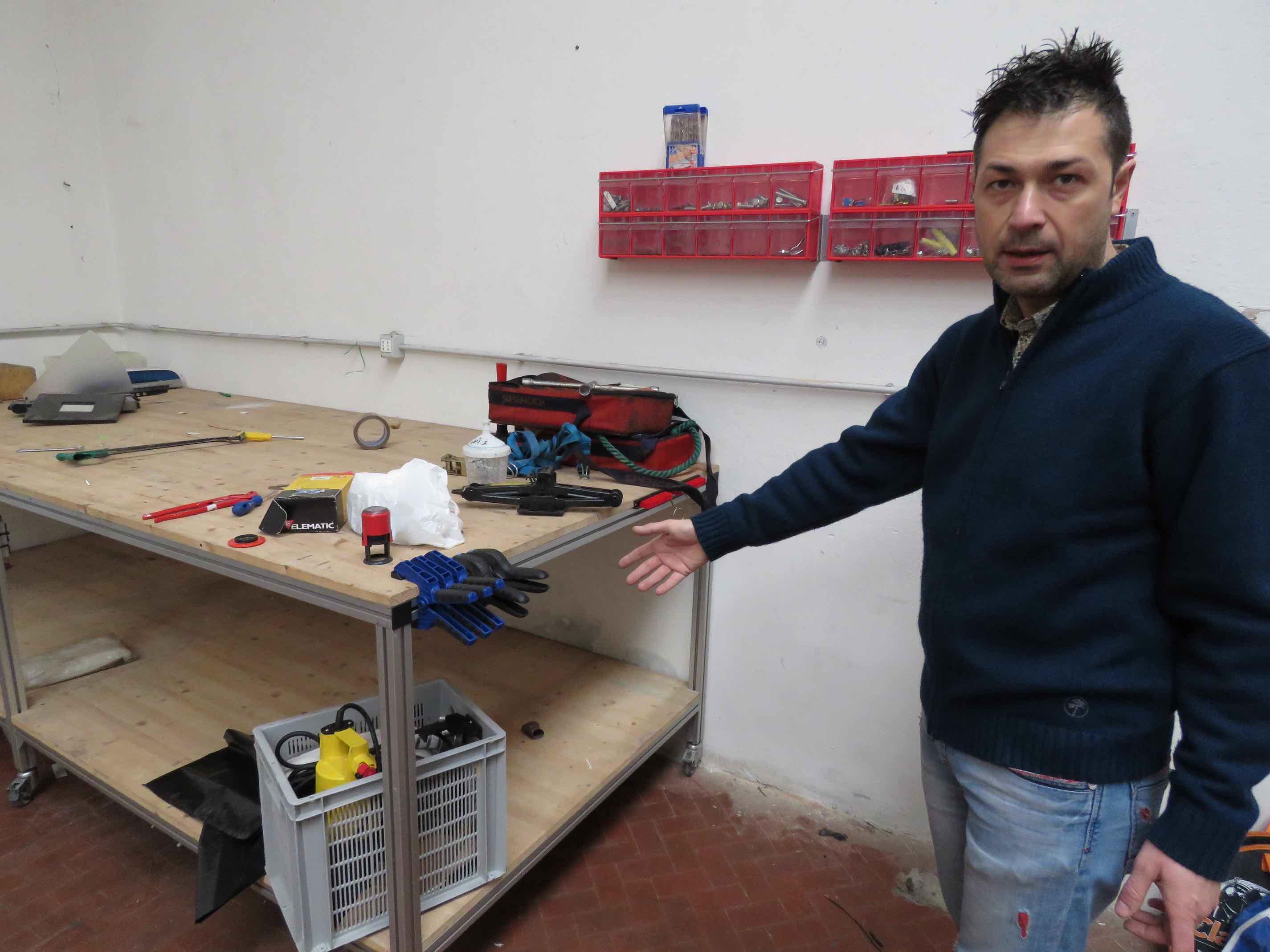 Un volontario mostra il banco da lavoro del magazzino quasi vuoto