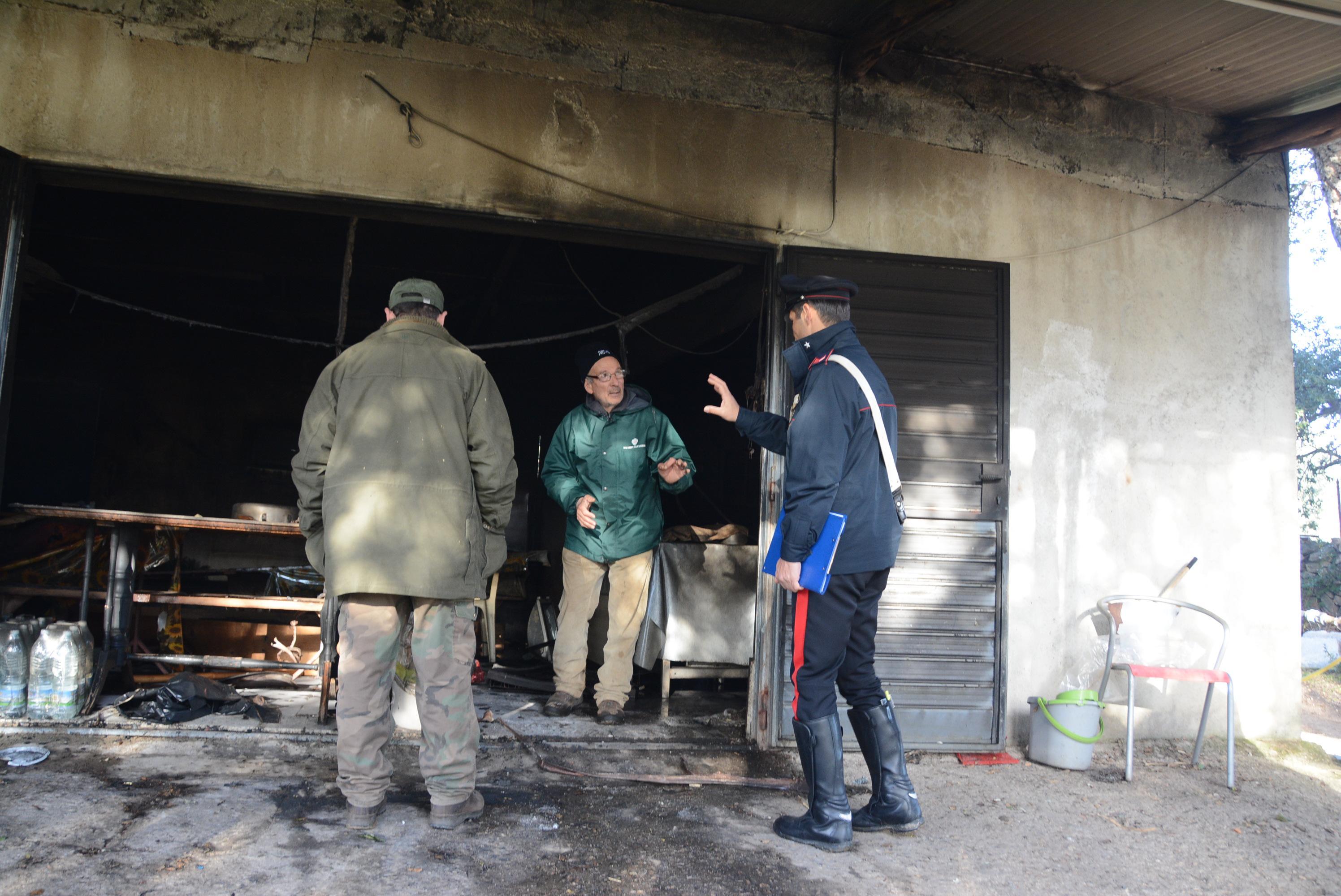 Un carabiniere parla con il proprietario della casa incendiata a Telti