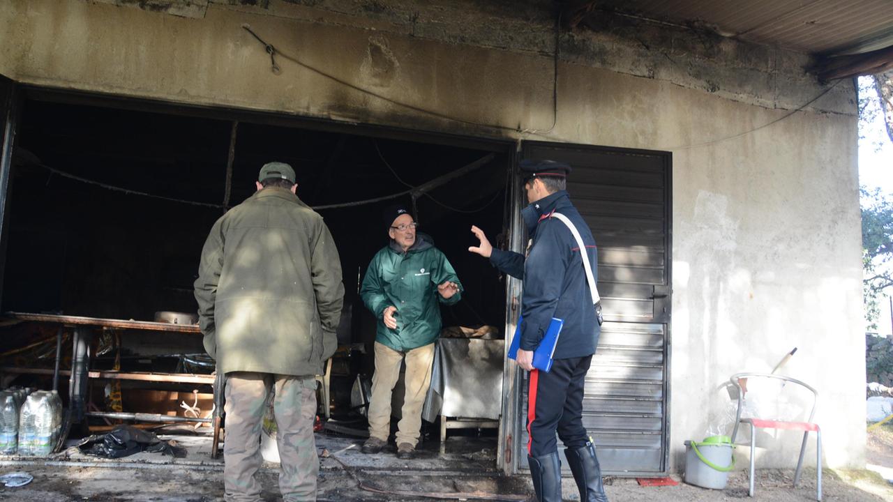 Un carabiniere parla con il proprietario della casa incendiata a Telti