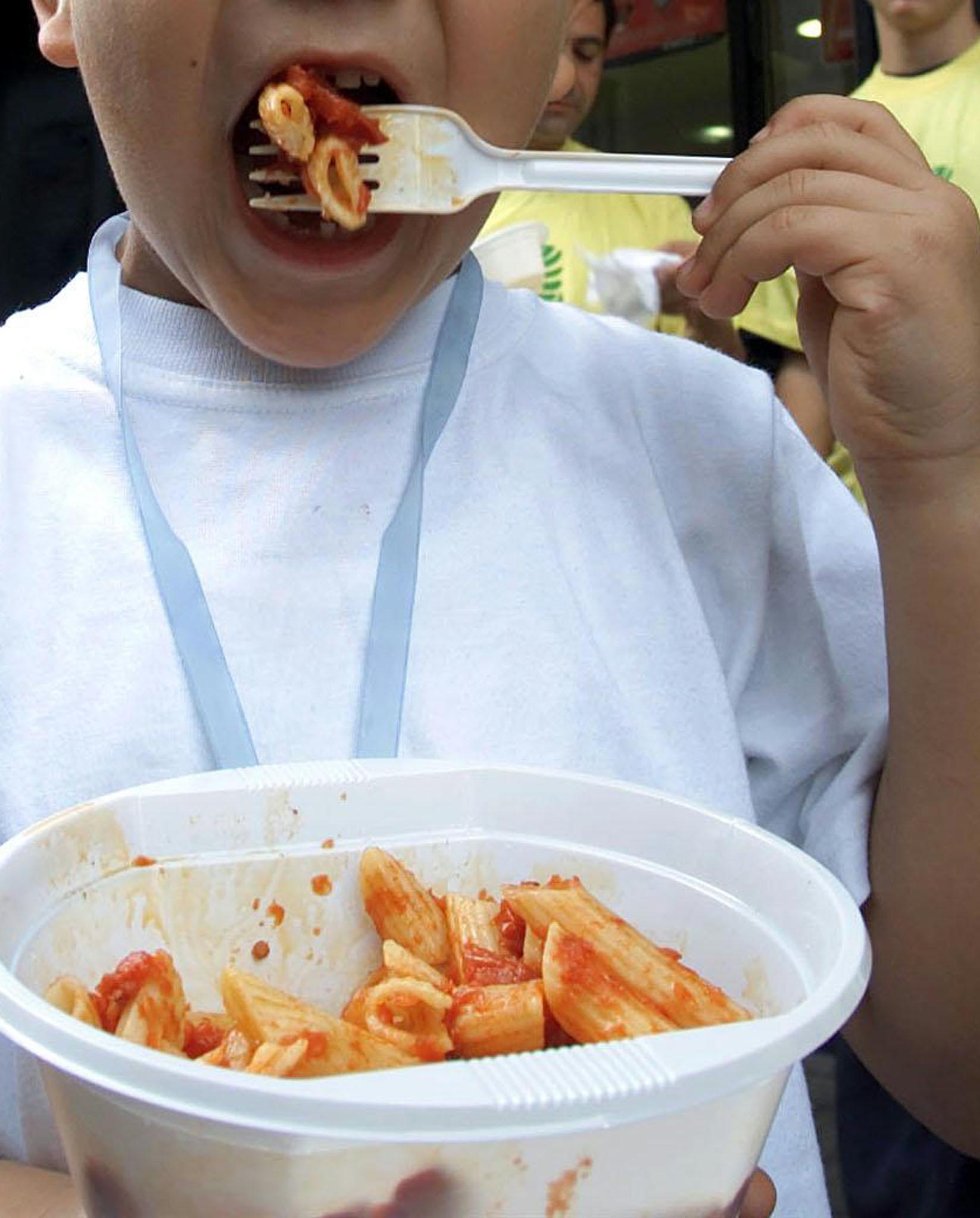 Un bambino con la pasta al pomodoro