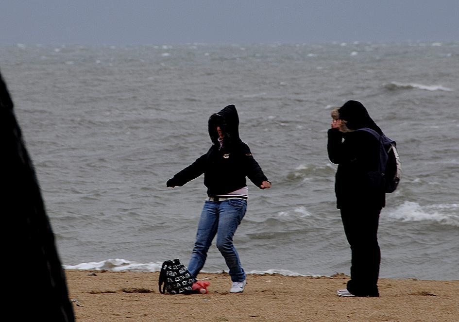 Due ragazze sfidano pioggia e vento sulla spiaggia di Torregrande