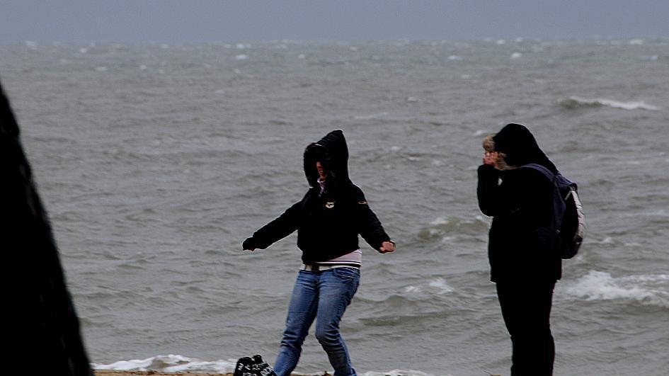 Due ragazze sfidano pioggia e vento sulla spiaggia di Torregrande