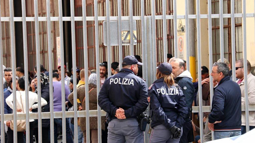 Le famiglie che hanno occupato l'ex deposito Atl e di qua dal cancello la polizia che controlla (Marzi Pentafoto)