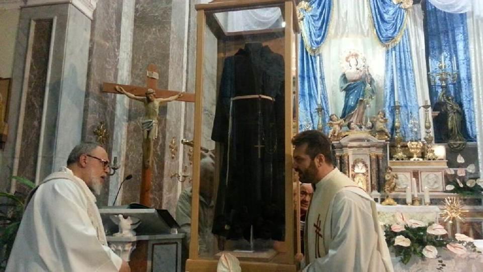 La reliquia del saio di padre Pio fra due sacerdoti (foto d'archivio)