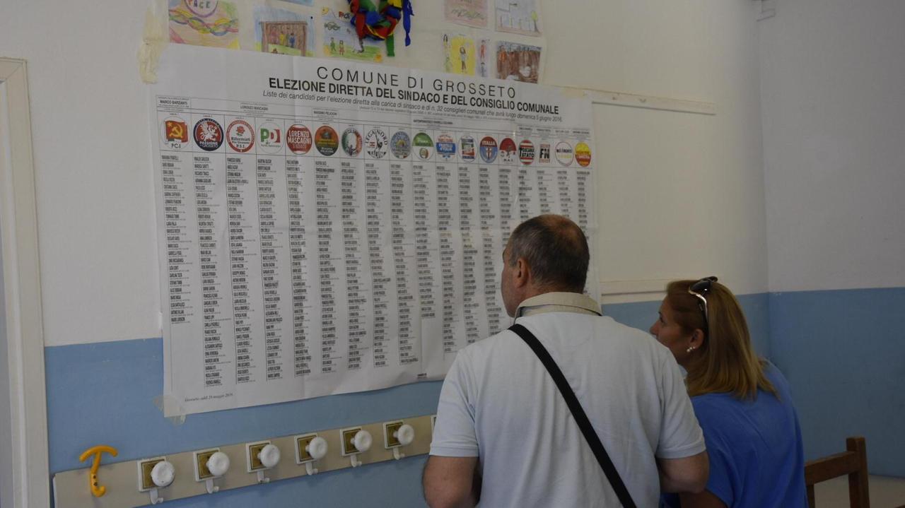Due elettori davanti alla lista dei candidati in un seggio grossetano (foto Agenzia Bf)