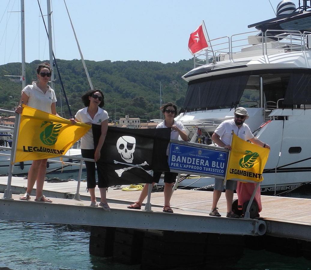 Gli esponenti di Legambiente con la bandiera nera nel porto di Marciana Marina