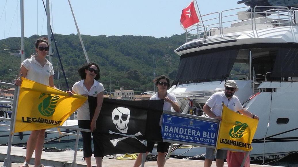 Gli esponenti di Legambiente con la bandiera nera nel porto di Marciana Marina