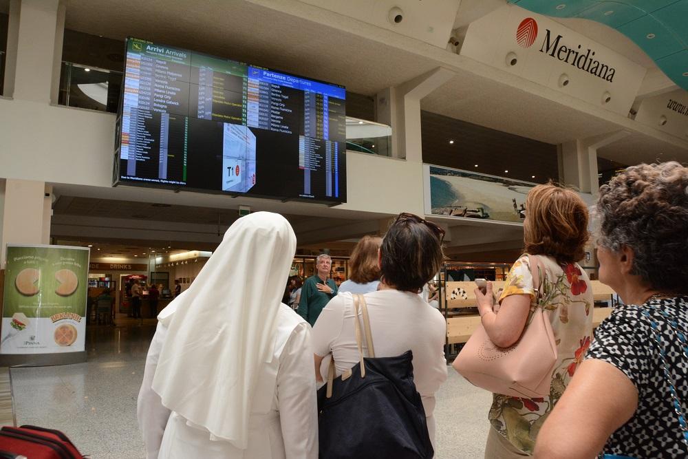 Una suora scruta il tabellone dei voli all'aeroporto di Olbia (Foto Gavino Sanna)