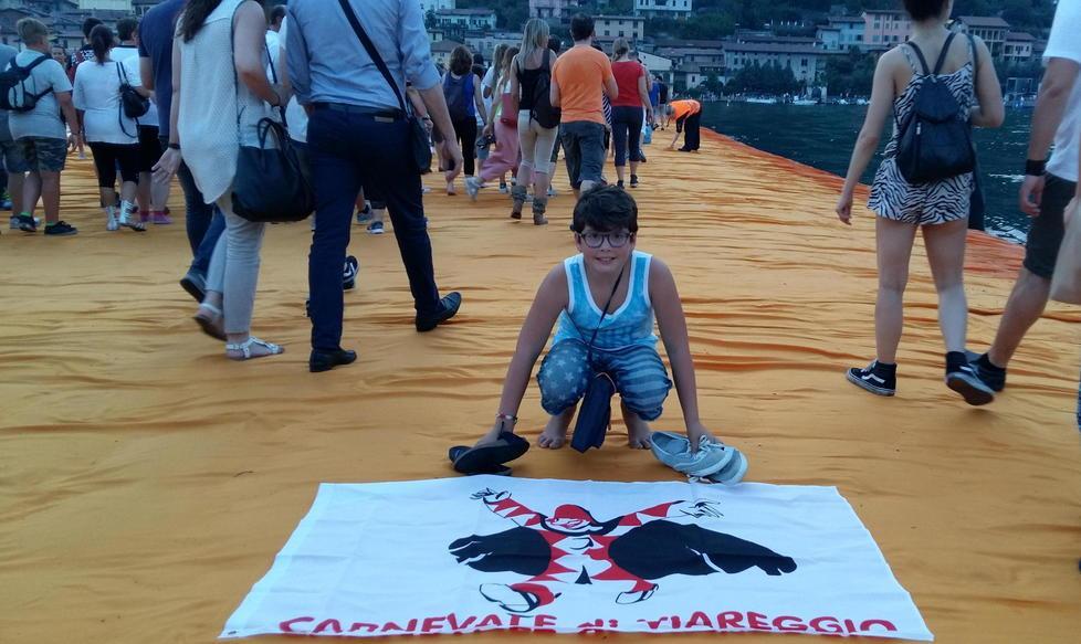Il piccolo Tommaso mostra con orgoglio la bandiera di Burlamacco sulla passerella di Christo