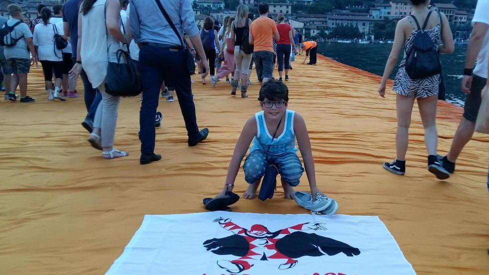 Il piccolo Tommaso mostra con orgoglio la bandiera di Burlamacco sulla passerella di Christo