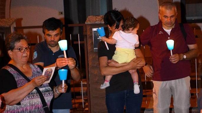 La mamma tiene in braccio la piccola durante la fiaccolata