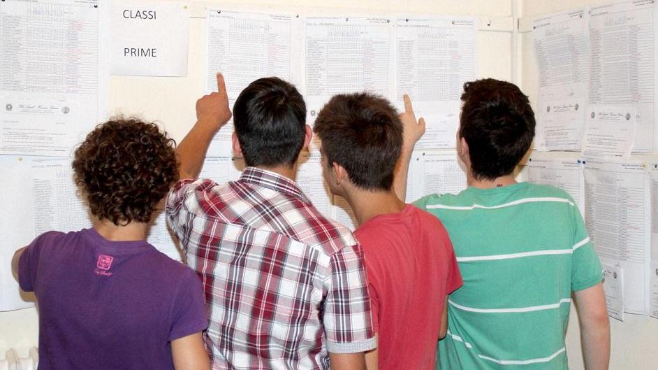 Un gruppo di studenti davanti ai tabelloni degli scrutini di una scuola superiore