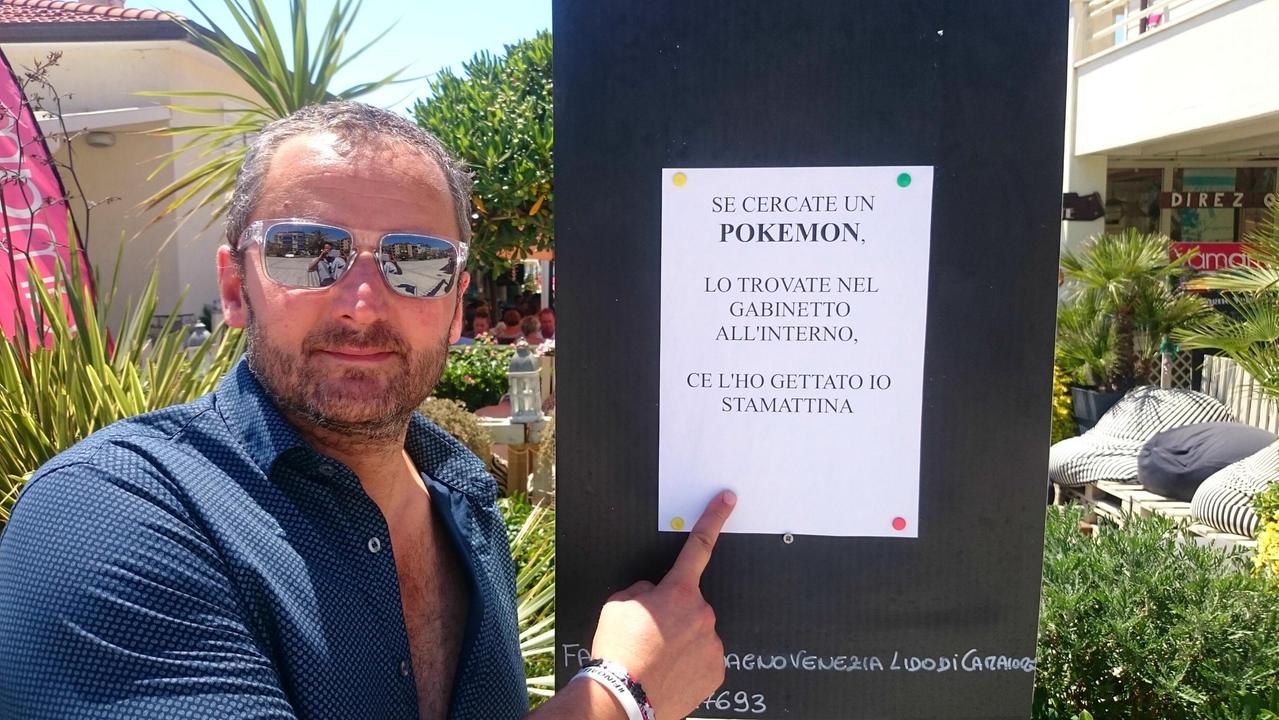Marco Daddio, titolare del bagno Venezia di Lido di Camaiore, mostra il cartello antipokèmon