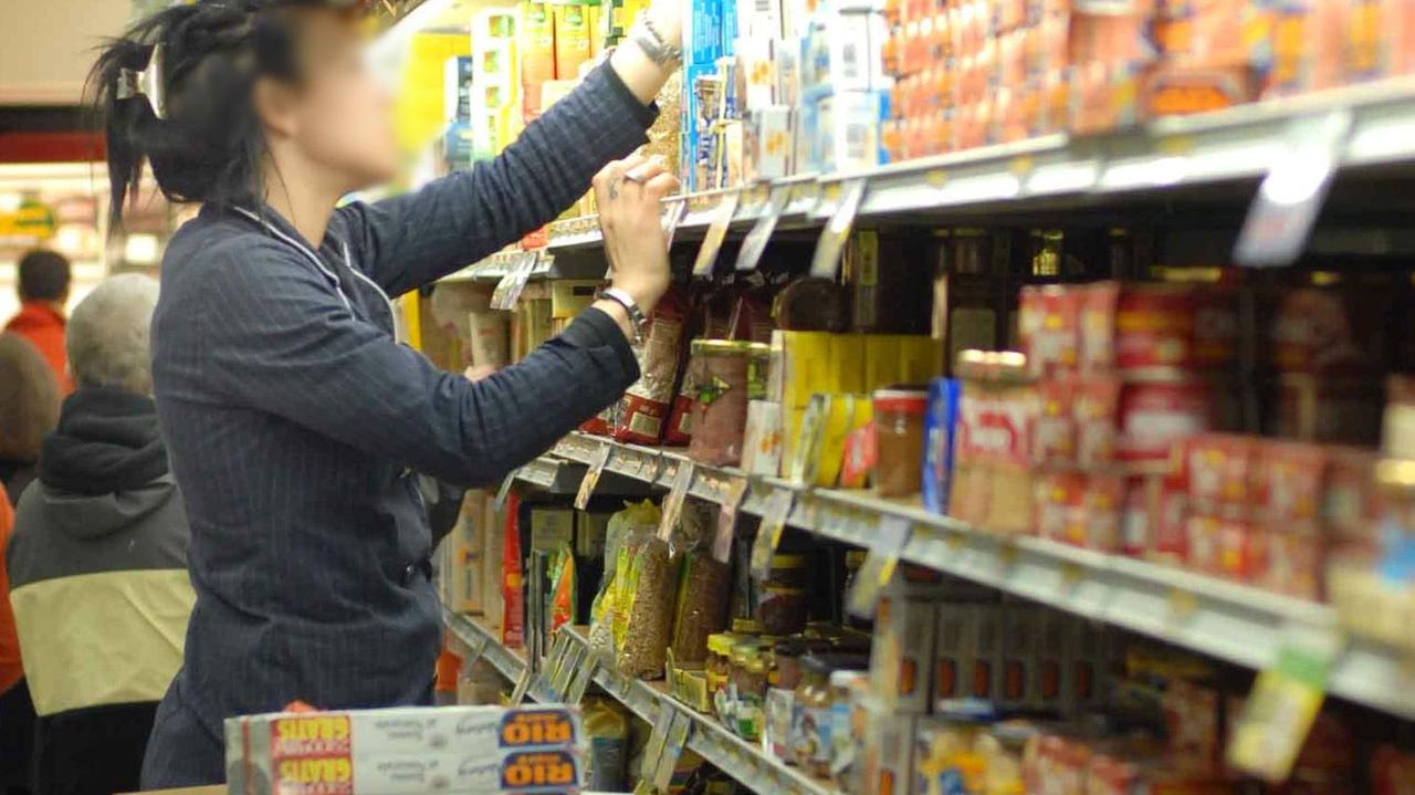 Una dipendente riempie gli scaffali in un supermercato (foto d'archivio)