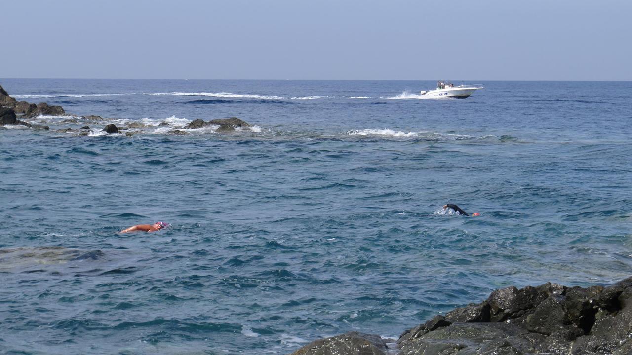 La barca che sfreccia nell’area vietata, sono i nuotatori che si fermano per farla passare