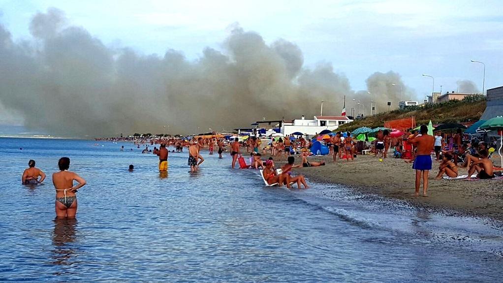 I bagnanti che cercano refrigerio a Platamona mentre gli incendiari prendono di mira la pineta