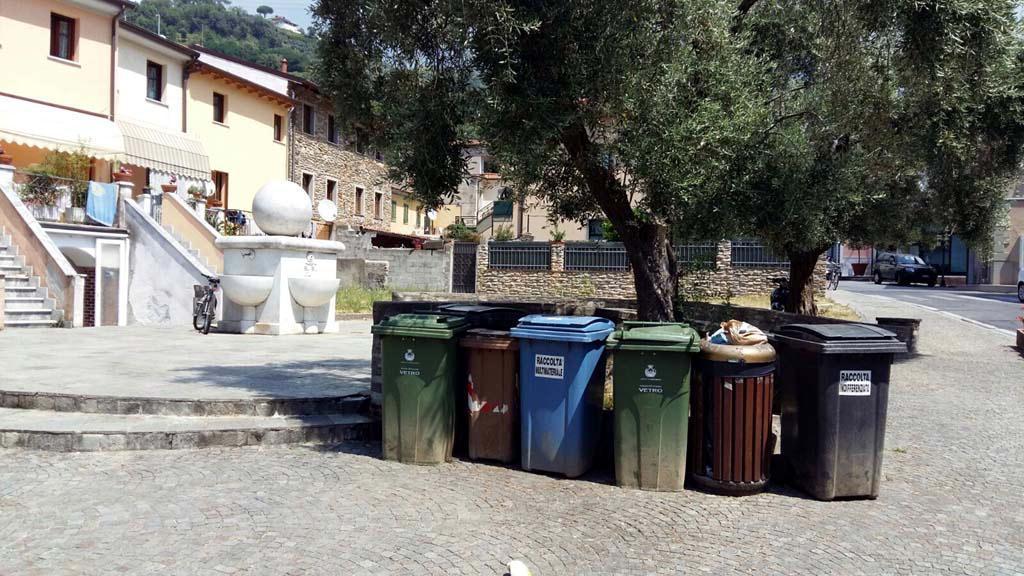 Cassonetti al centro di piazza Tenco, a due passi dalle panchine