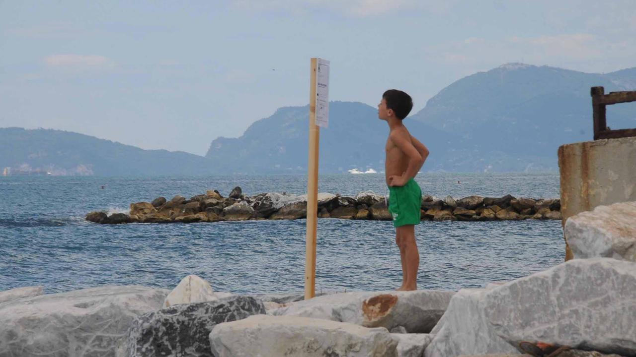 Un ragazzo mentre legge il divieto di balneazione dei giorni scorsi
