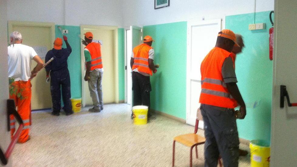 Alcuni dei profughi durante i lavori all'interno di una scuola di Cecina
