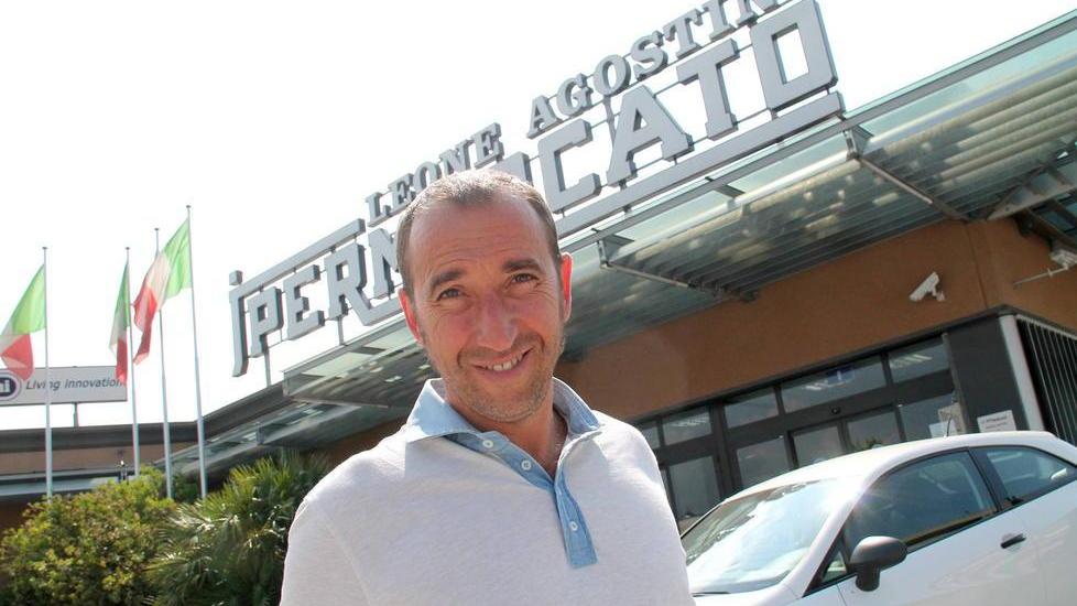 Diego Agostini di fronte all'insegna dell'Jpermercato