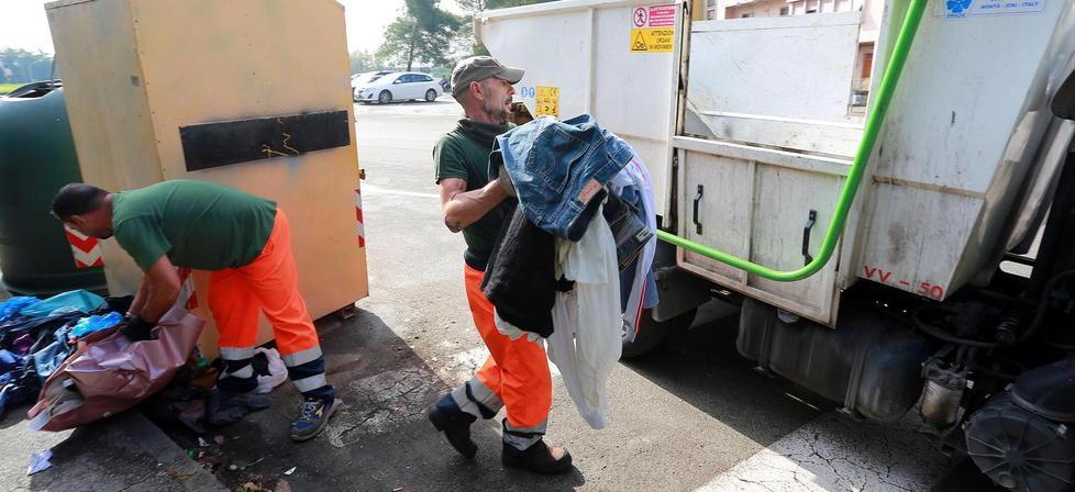 Gli operatori incaricati da Publiambiente di ripulire intorno ai cassonetti degli abiti usati (Foto Agenzia Carlo Sestini)