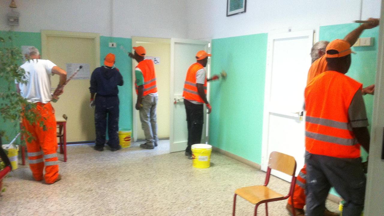 Profughi imbiancano una scuola