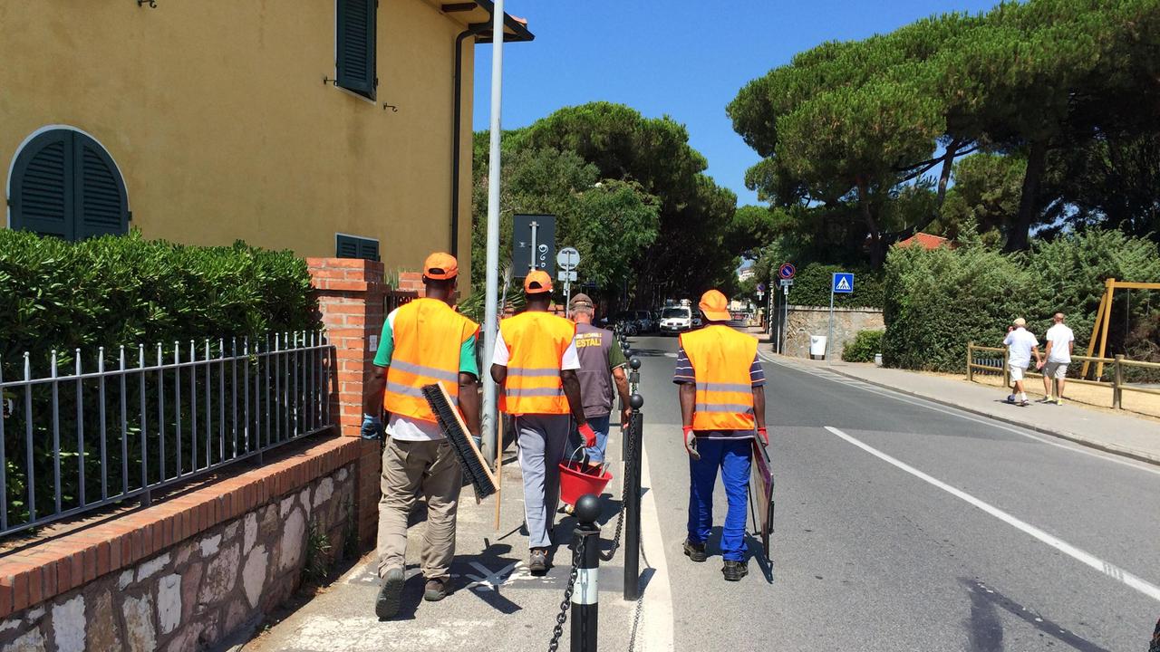 Alcuni profughi impegnati nella pulizia delle strade a Marina di Cecina