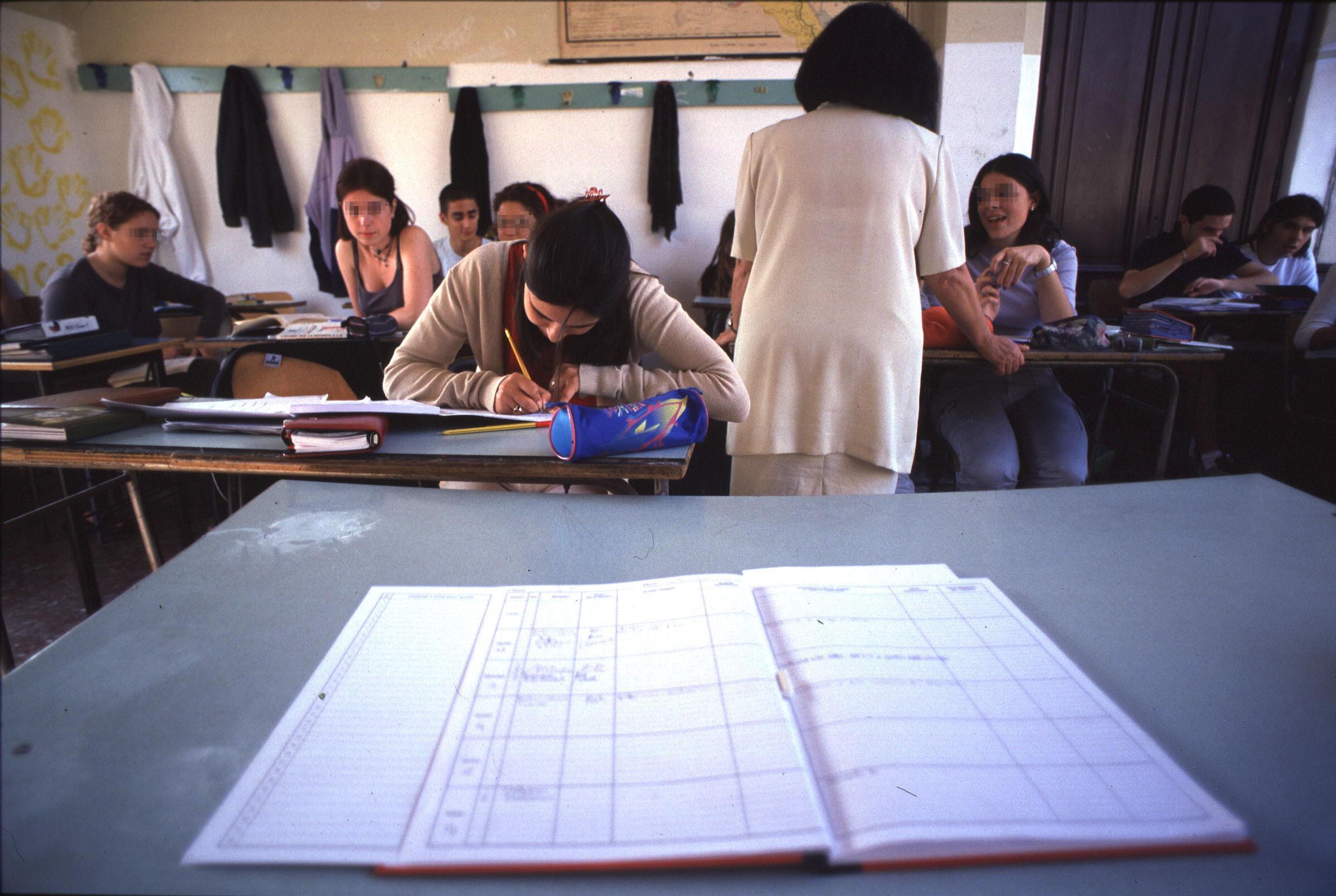 Una insegnante nella sua classe in una scuola superiore: in primo piano la cattedra