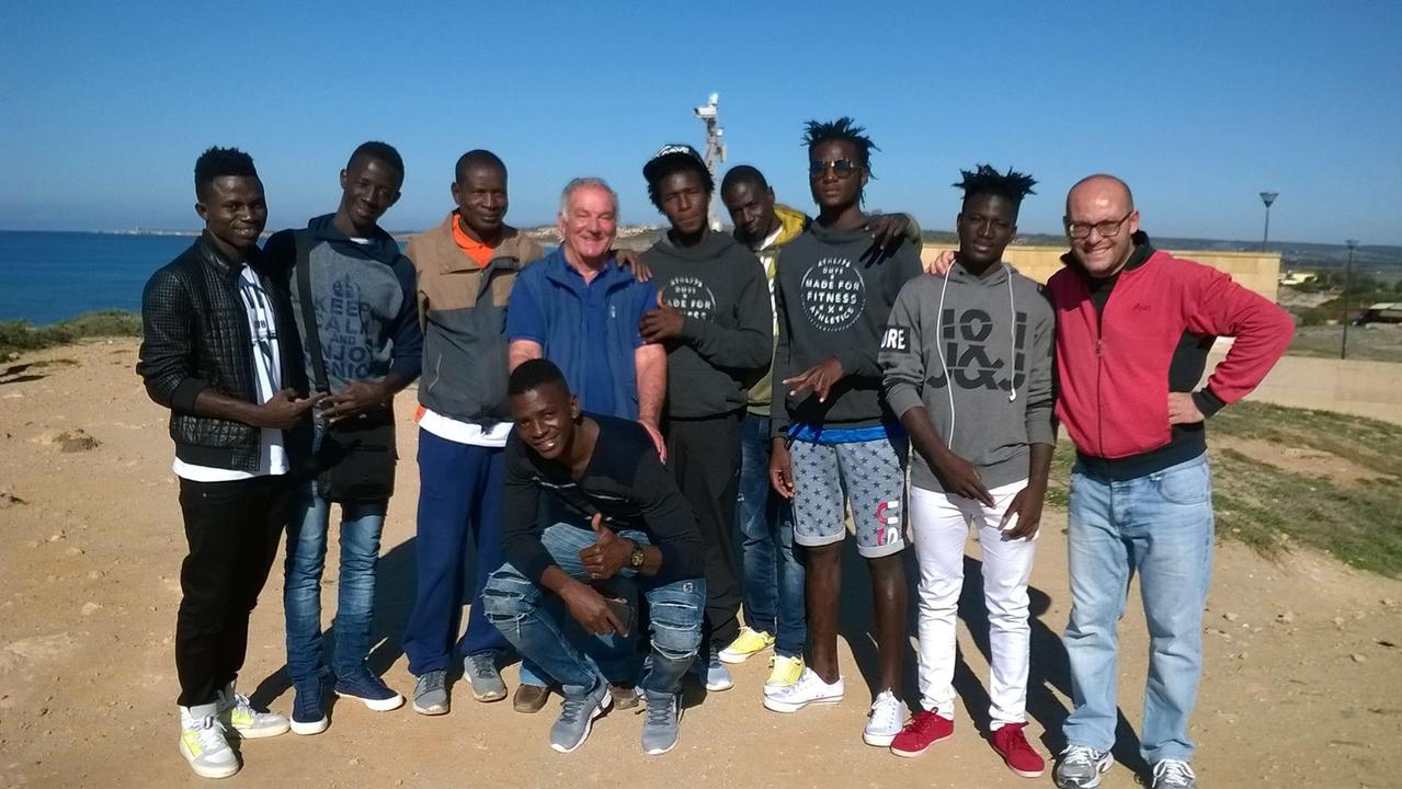 Antonio Bellinzas (al centro nella foto) con un altro volontario e un gruppo di migranti