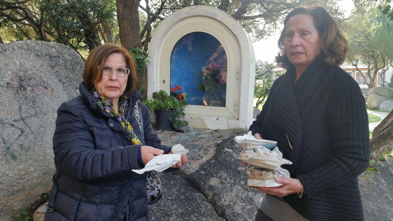 Due donne mostrano i resti della statua della Madonnina davanti alla teca
