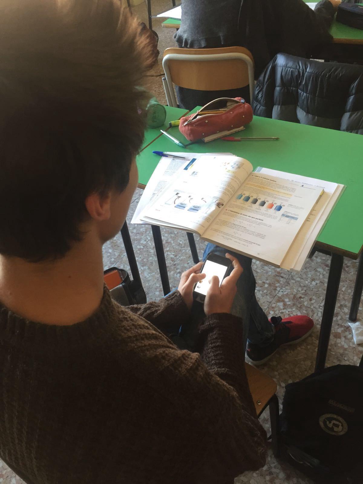 Uno studente "impegnato" con il telefonino in classe