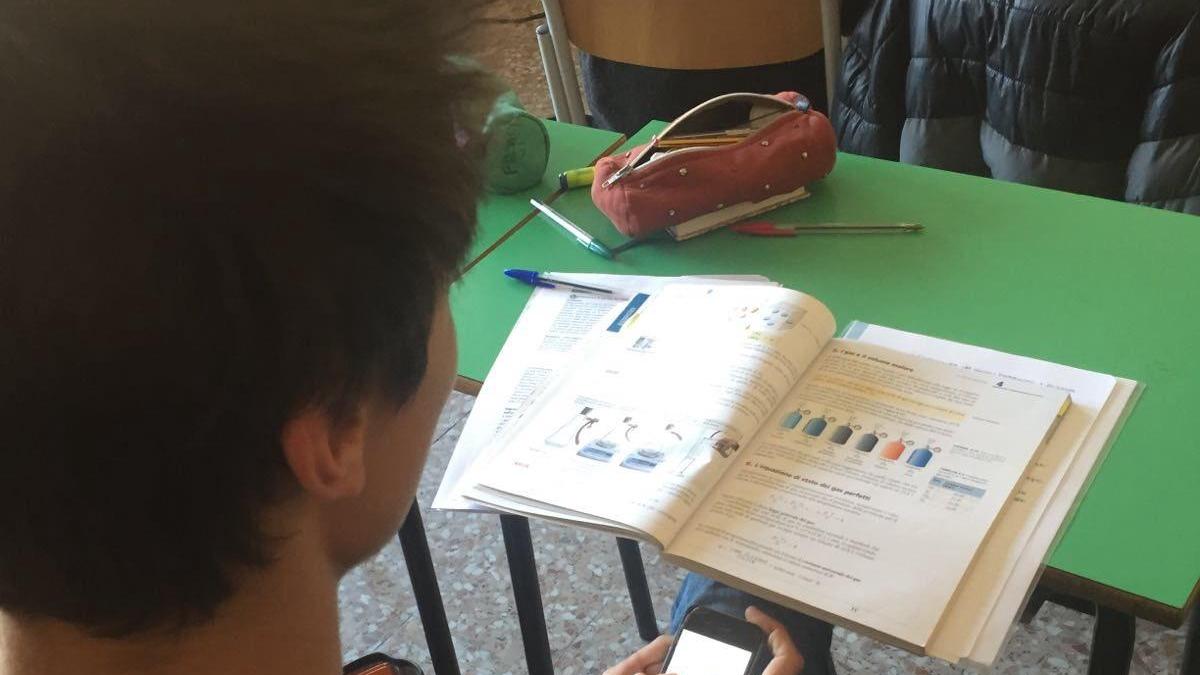 Uno studente "impegnato" con il telefonino in classe