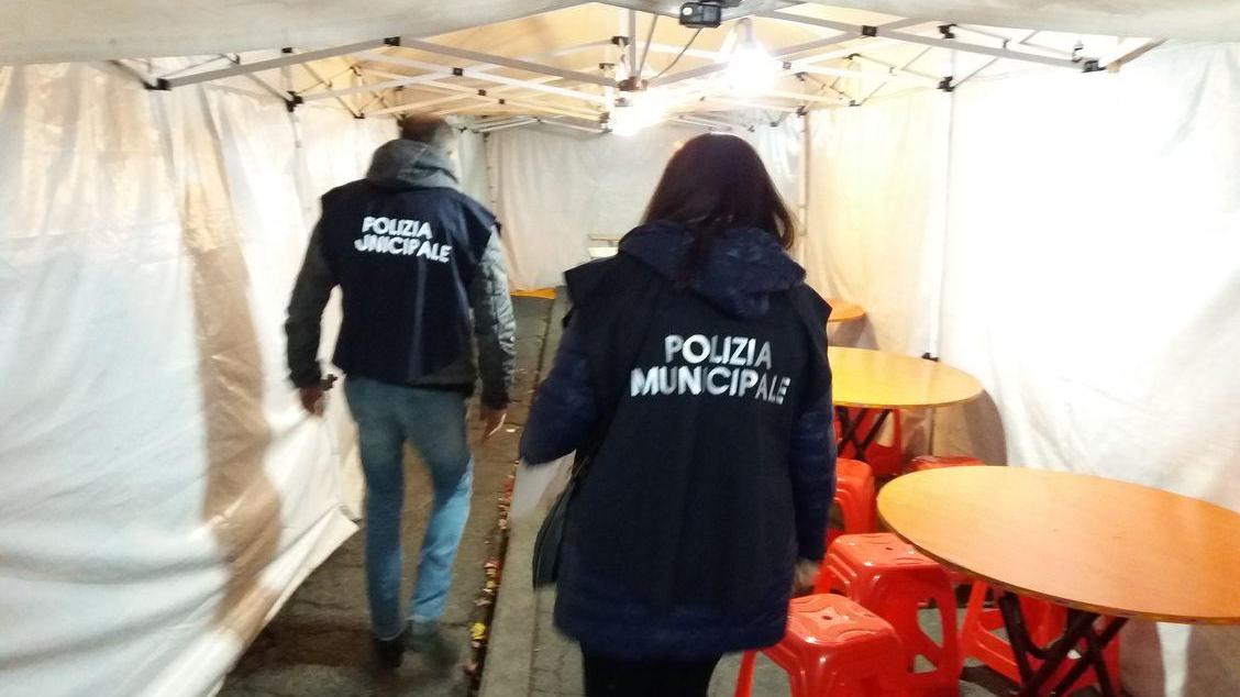 Controlli dei vigili anti-contraffazione in un esercizio di commercio ambulante