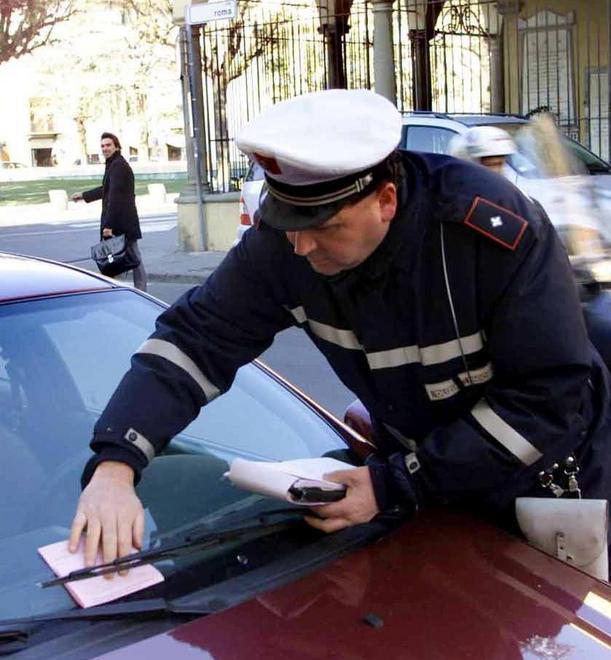 Un agente di polizia municipale lascia una multa sotto il tergicristallo di un'auto (Foto d'archivio) 