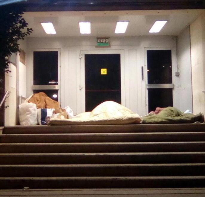 L'ingresso della ex Banca commerciale: la coppia e l'amico mentre dormono sotto le coperte